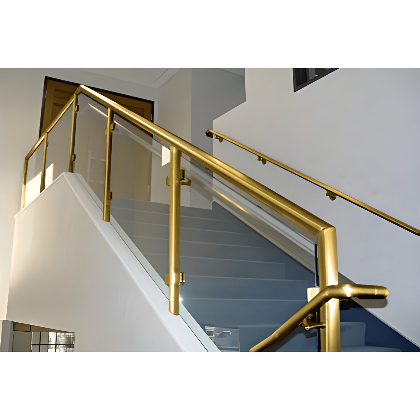Polished brass welded post railing system (PR1540PB) with glass infill on interior staircase.