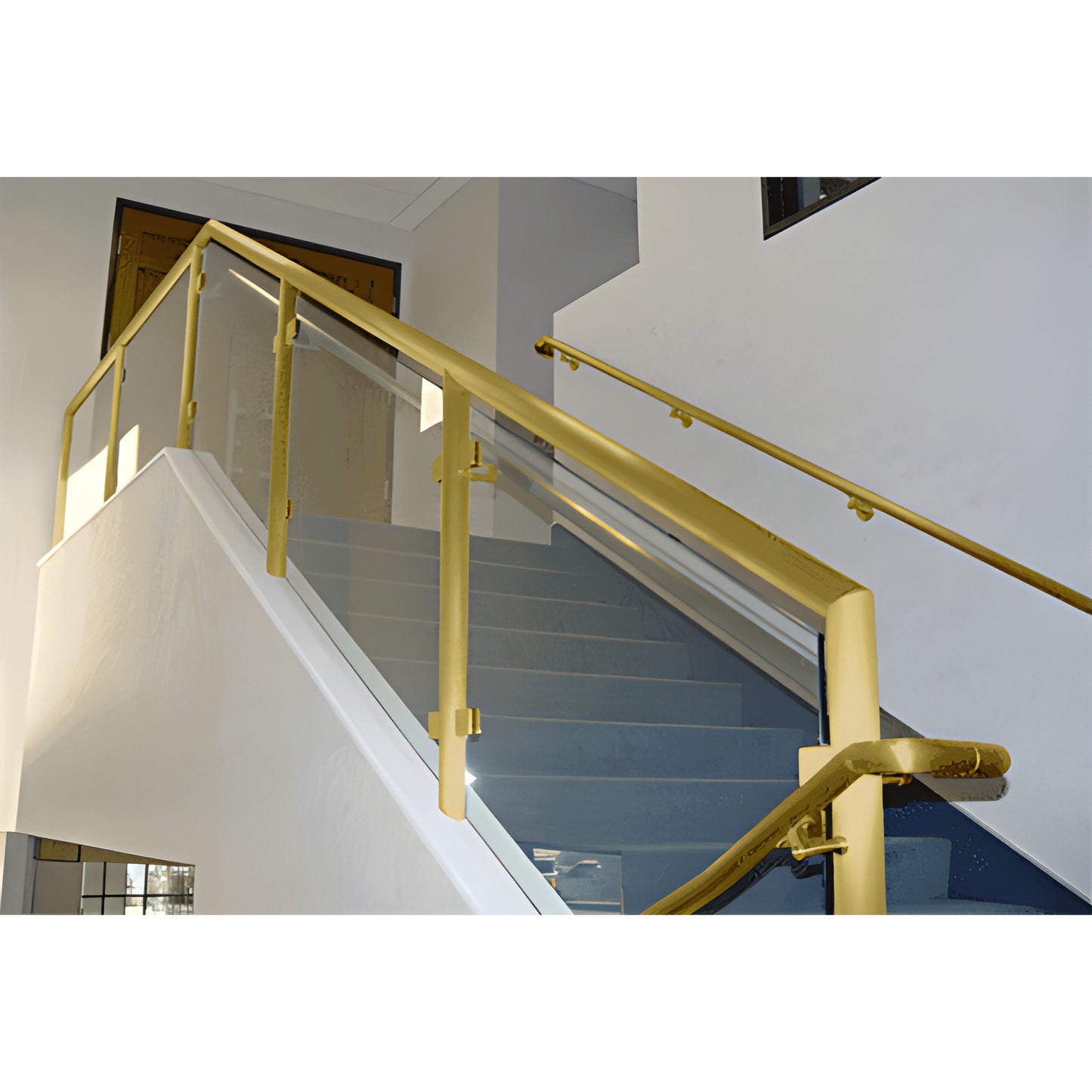 PR1540SB satin brass welded post railing with glass infill and matching handrail on interior stair.