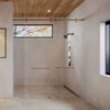 A close-up view of the satin brass Brixen series sliding shower door system featuring concealed top rollers and glass panels.