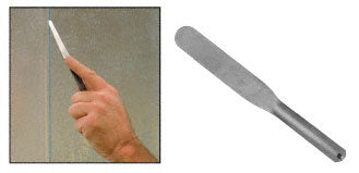 A hand uses a flat, flexible stainless steel spatula to work along a seam on a surface.