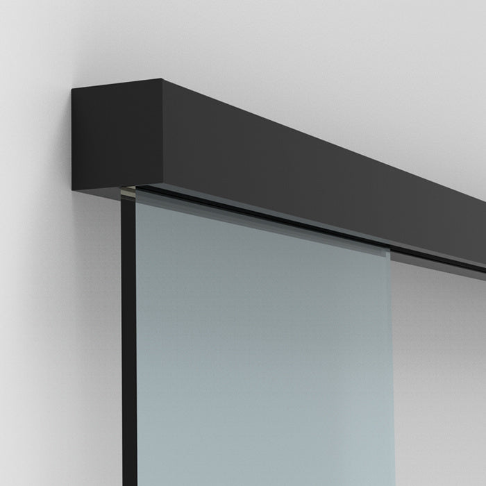 A matte black sliding door track mounted to a wall with a glass panel installed.
