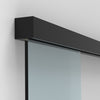 A matte black sliding door track mounted to a wall with a glass panel inserted.