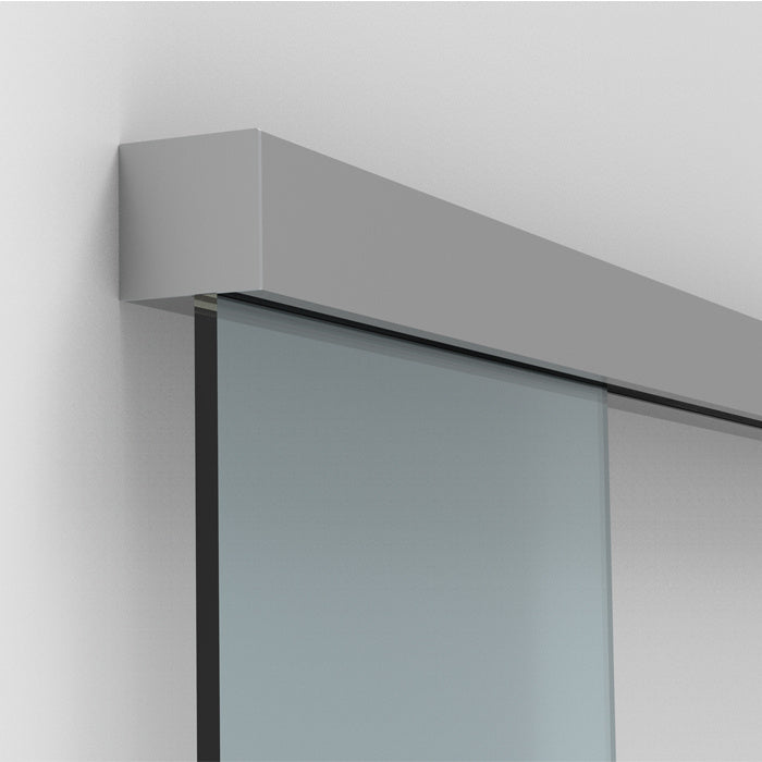A satin anodized sliding door track mounted to a wall above a glass panel.