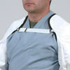 A person wears a white garment secured with the white elastic shoulder strap and metal clips.