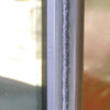The gray pile weatherstrip installed along the edge of a metal storefront door frame.