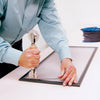 A person using a screen rolling tool to press black spline into a window screen frame.