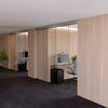 A modern office interior featuring the CRL50 series telescoping glass door system installed as a room partition.