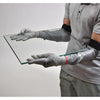 A person wearing grey cut-resistant sleeves while safely handling a large sheet of glass.