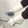 A person wears a pair of white polyester mesh wrist protectors while handling a sheet of glass.