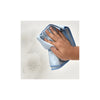 A hand uses a blue glass cloth to wipe a surface clean.