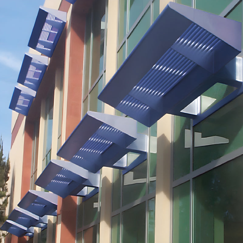 Blue powder-coated CRL7700 Series sunshade louvers (SKU AW7700PTC) mounted above a commercial glass facade in a row.