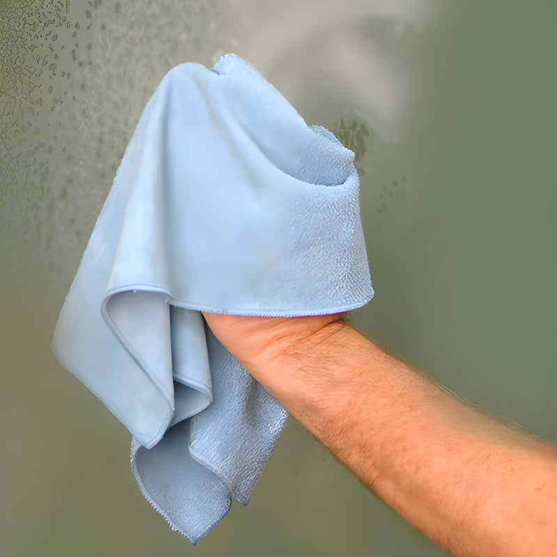 Hand wiping glass with light-blue 16 16 reusable microfiber cloth, SKU MFW12, sold in 12-pack