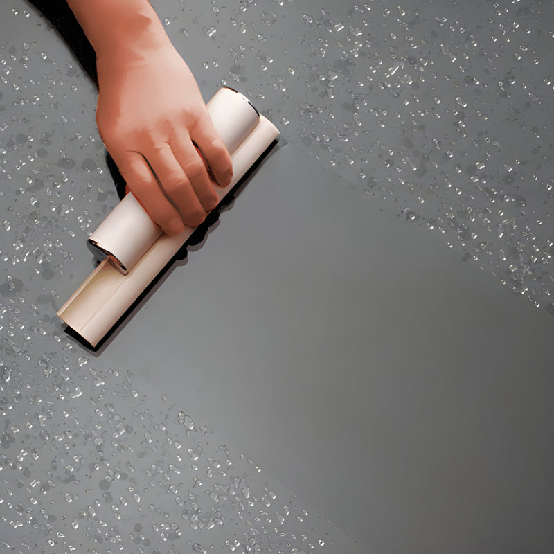 White dual-blade squeegee (SKU SQWC1) with chrome end caps wiping water from a glass shower door